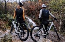 two gravel riders, one male and one female admiring a waterfall standing by their Riverside RCR grvael bikes